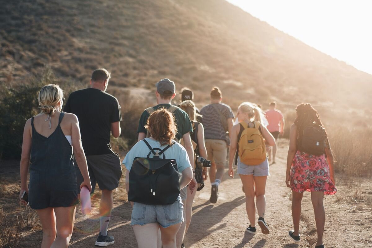 A group of people hiking up a steep hill at sunset.