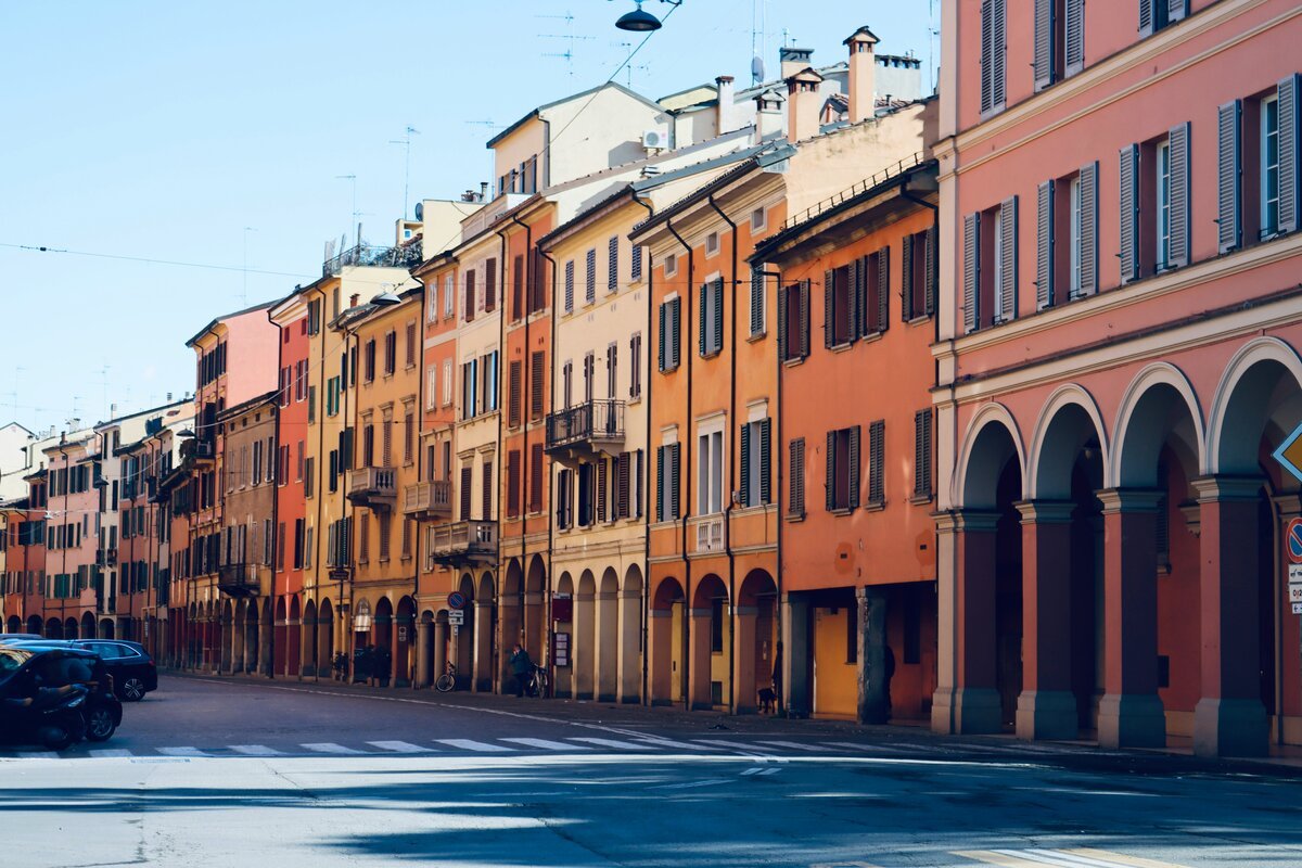 Bologna, Emilia-Romagna, Italy. Beautiful street with colorful row housing, each with multiple arches on the ground floor,