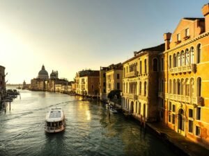 Venice's Grand Canal. A cloud free and romantic sunrise in the background upon the canal with a single water bus vaporetto traveling on its calm water.